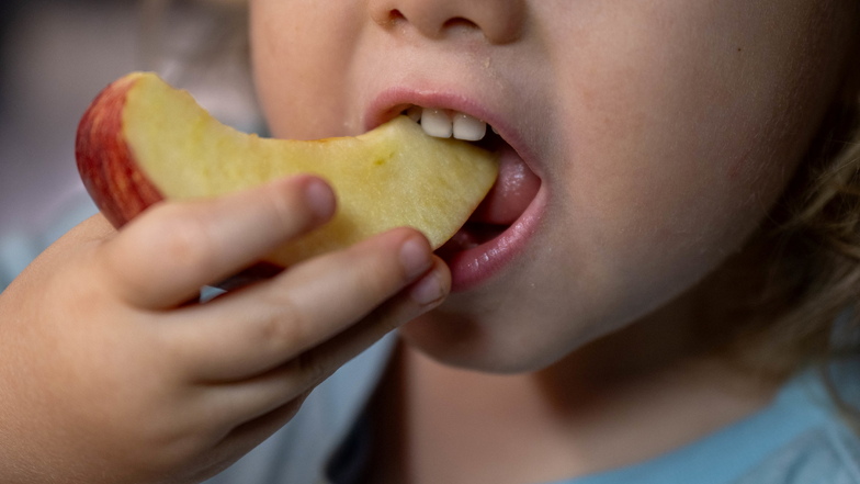Ein Kind isst ein Stück Apfel.