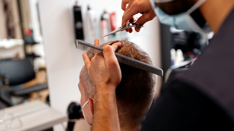 Ein Friseur schneidet einem Kunden die Haare ab. Mit den Haarresten lässt sich verschmutztes Wasser reinigen.