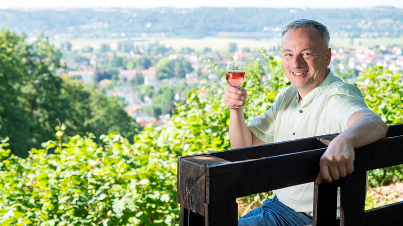 Carsten Puhlmann vom Vorstand der Weinbaugemeinschaft Radebeul-Niederlößnitz sitzt auf einer von Vereinsmitgliedern selbstgebauten Bank und genießt Wein und Aussicht in der Besenschänke "Zur Gemse".