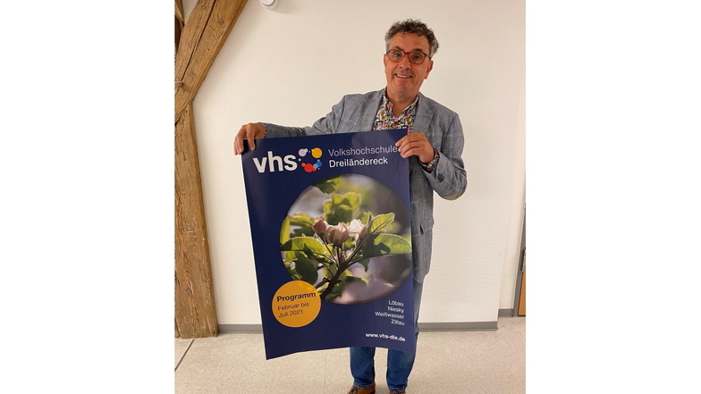VHS-Chef Matthias Weber mit einem Plakat des letzten Semesters, das wegen Corona gar nicht stattgefunden hat. Weber bietet das Plakat meistbietend als Liebhaberstück an.