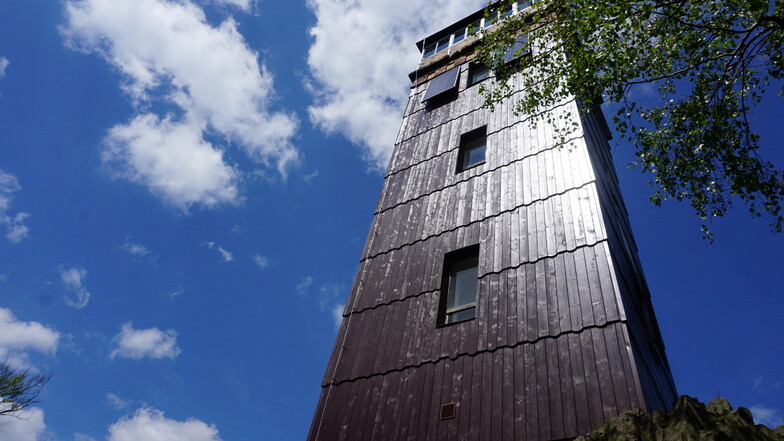 Der Wolfsbergturm mit neuer glänzender Holzverkleidung und den typischen Basaltsäulen an seinem Fundament.