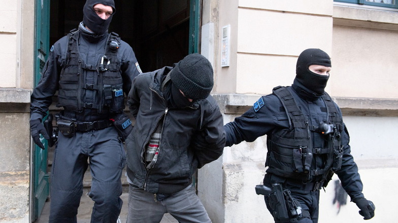Polizisten führen bei der Razzia im Dresdner Stadtteil Pieschen einen Tatverdächtigen aus einem Mehrfamilienhaus.