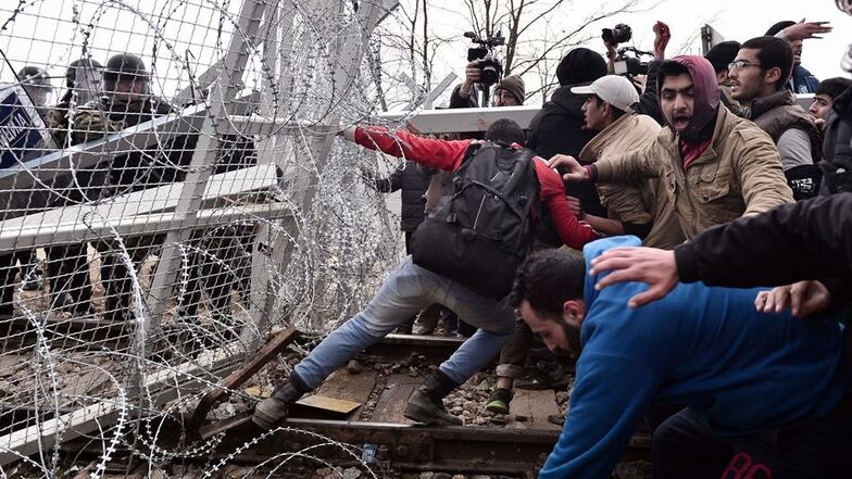 Flüchtlinge zerren am Grenzzaun zu Mazedonien.