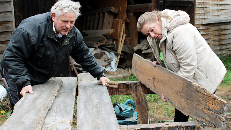 Edelbert Niedan (Zimmerer) und Cornelia Schnippa (Vorsitzende des Fördervereins HeimatHOF Lieske) sichten Stücke des originalen Holzes: Was ist wiederverwendbar – und was wird auf Grund zu starker Abnutzung durch neue Bauelemente ersetzt werden müsse