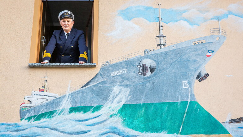 Der ehemalige Seefahrer Peter Gneuß blickt aus dem Fenster seines Hauses in Ottendorf. Seinen einstigen Arbeitsplatz hat der Kapitän auf die Außenwand malen lassen.