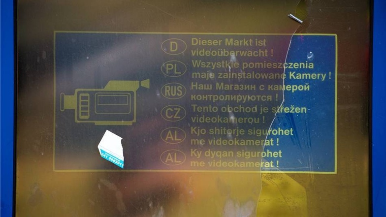 An einer Tür  klebt noch ein Aufkleber, der auf eine Videoüberwachung in deutscher, polnischer, russischer, tschechischer und albanischer Sprache hinweist.