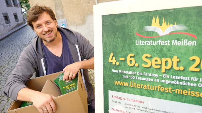 Daniel Bahrmann, der dem Organisatorenteam des Meißner Literaturfestes vorsteht, verteilt die druckfrischen Programmhefte.