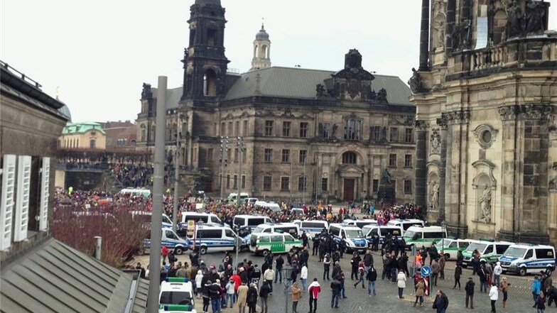Unweit der Pegida-Kundgebung haben sich Gegendemonstranten auf dem Schlossplatz versammelt. Der Durchgang ist von mehreren Reihen Polizeiautos abgesichert.