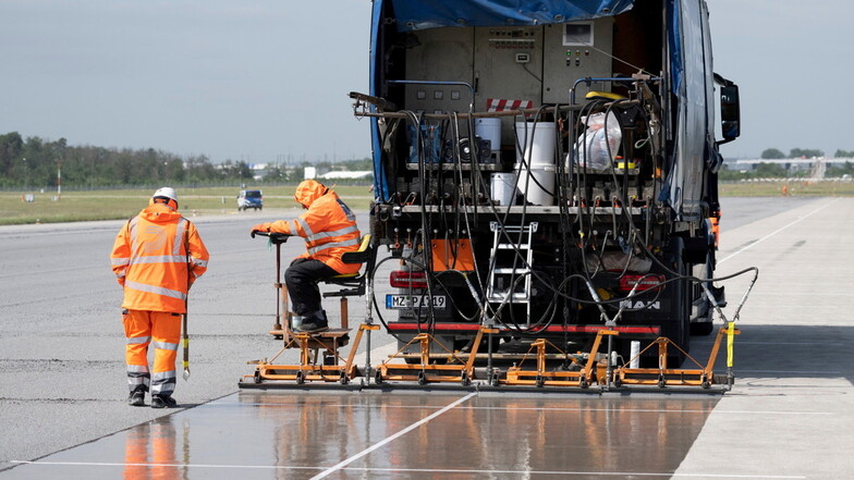 Eine spezielle Flüssig-Grundierung bringen Arbeiter mit einem Spezialfahrzeug auf der Landebahn Nordwest auf dem Flughafen in Frankfurt auf.