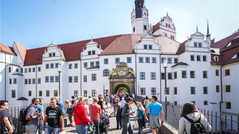 Besucher schlendern vor Schloss Hartenstein in Torgau.