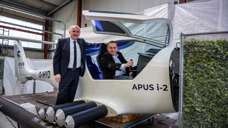 Markus Mütsch, Geschäftsführer des Instituts KVB, zeigt Staatsminister Thomas Schmidt (links) ein Kleinflugzeug, das mit besonderen Wasserstofftanks ausgerüstet ist.