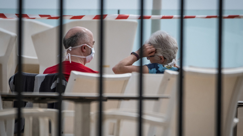 Ein Paar sitzt mit Mundschutz am Swimmingpool des Hotels H10 Costa Adeje Palace in Teneriffa. Das Hotel wurde wegen Coronavirus-Fällen unter Quarantäne gestellt.