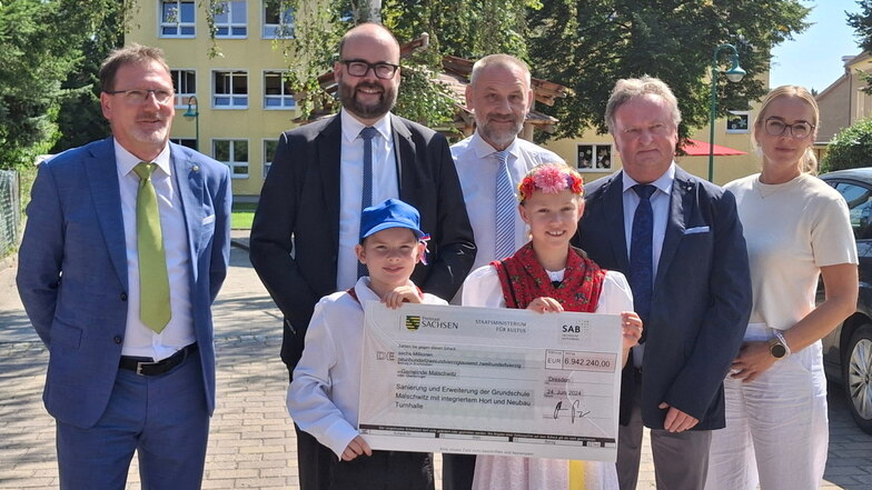 Minister Christian Piwarz (2.v.l.) übergab den Förderscheck im Beisein der Kleinbautzener Hortleiterin Elisa Nehrig (r.), des Schulleiters Michael Biskop (2.v.r.) und des Landtagsabgeordneten Marko Schiemann (M.) an Bürgermeister Matthias Seidel (l.).