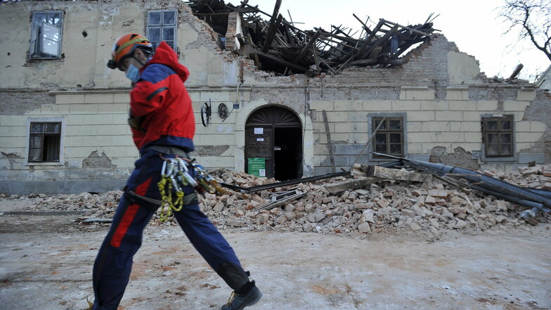 Kroatien, Petrinja: Ein Mitglied der Rettungskräfte geht vor den Trümmern eines eingestürzten Hauses vorbei.
