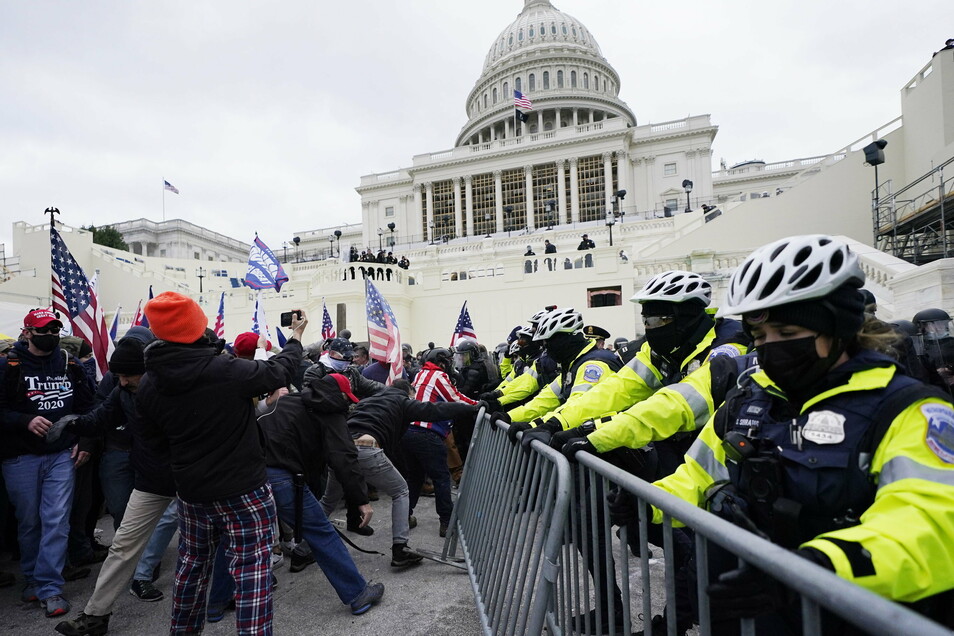 Trump supporters attempt to break a barrier in front of the Capitol.