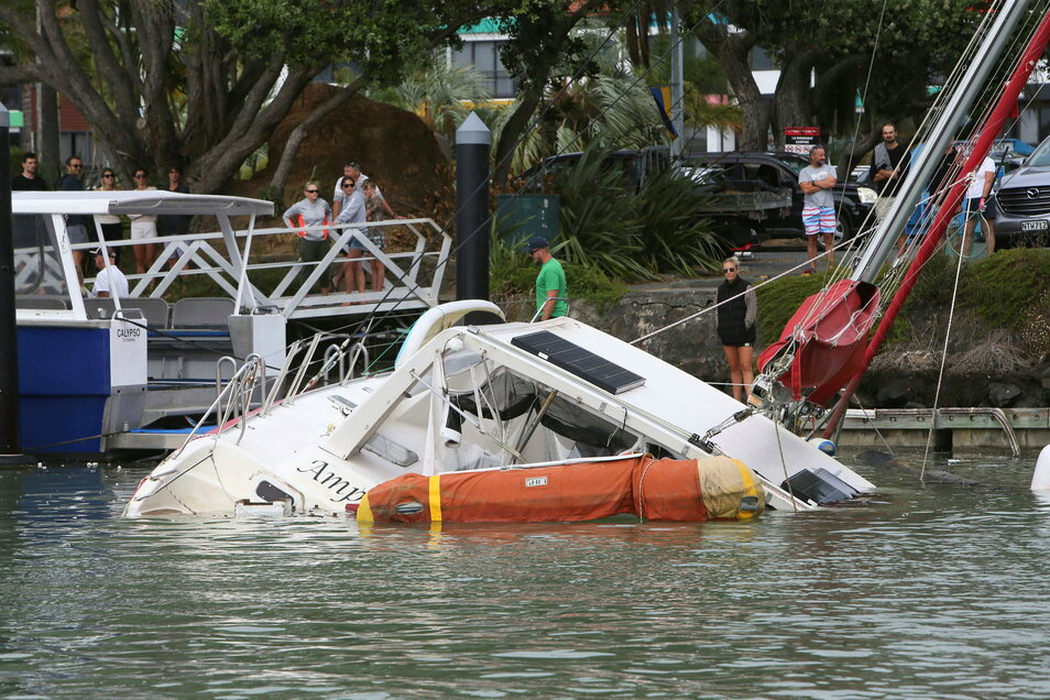 In Tuticorin, New Zealand, people stand on the harbor and watch the boat in danger of sinking in the harbor.