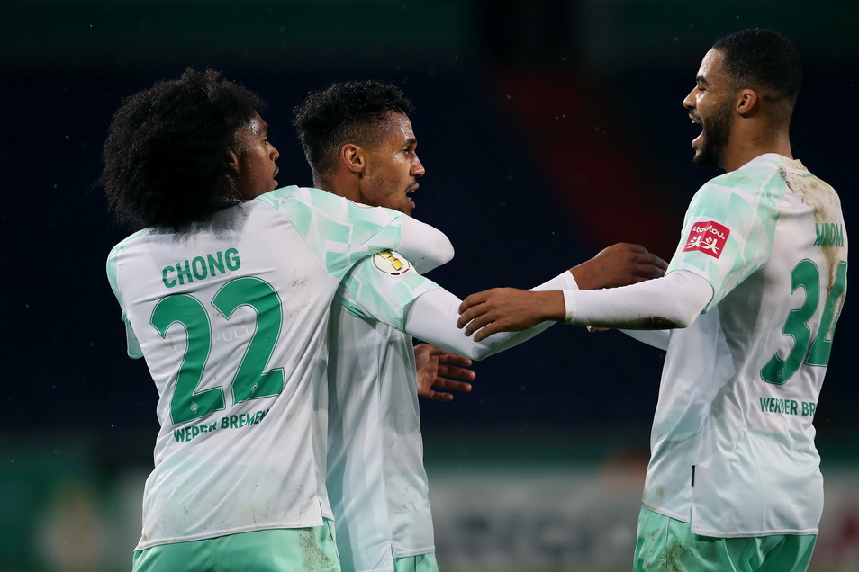 Bremen's Theodor Gebre Selassie (M) celebrates after scoring a 1-0 lead with Tahith Chong (l) and Jean Manuel Mbom (r).